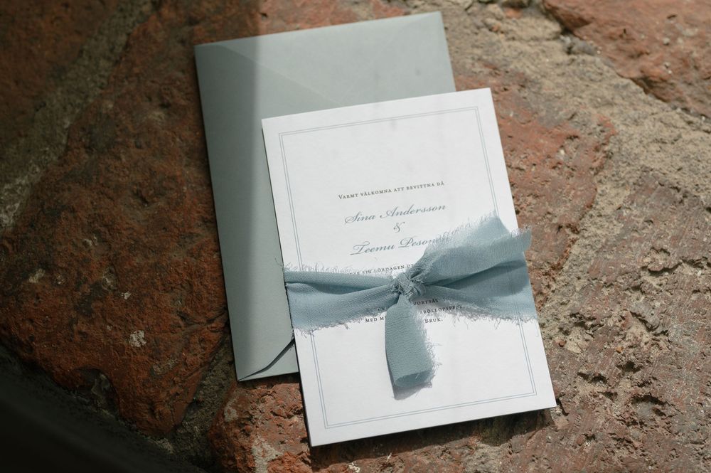 Elegant white wedding invitations with light blue ribbon details.
