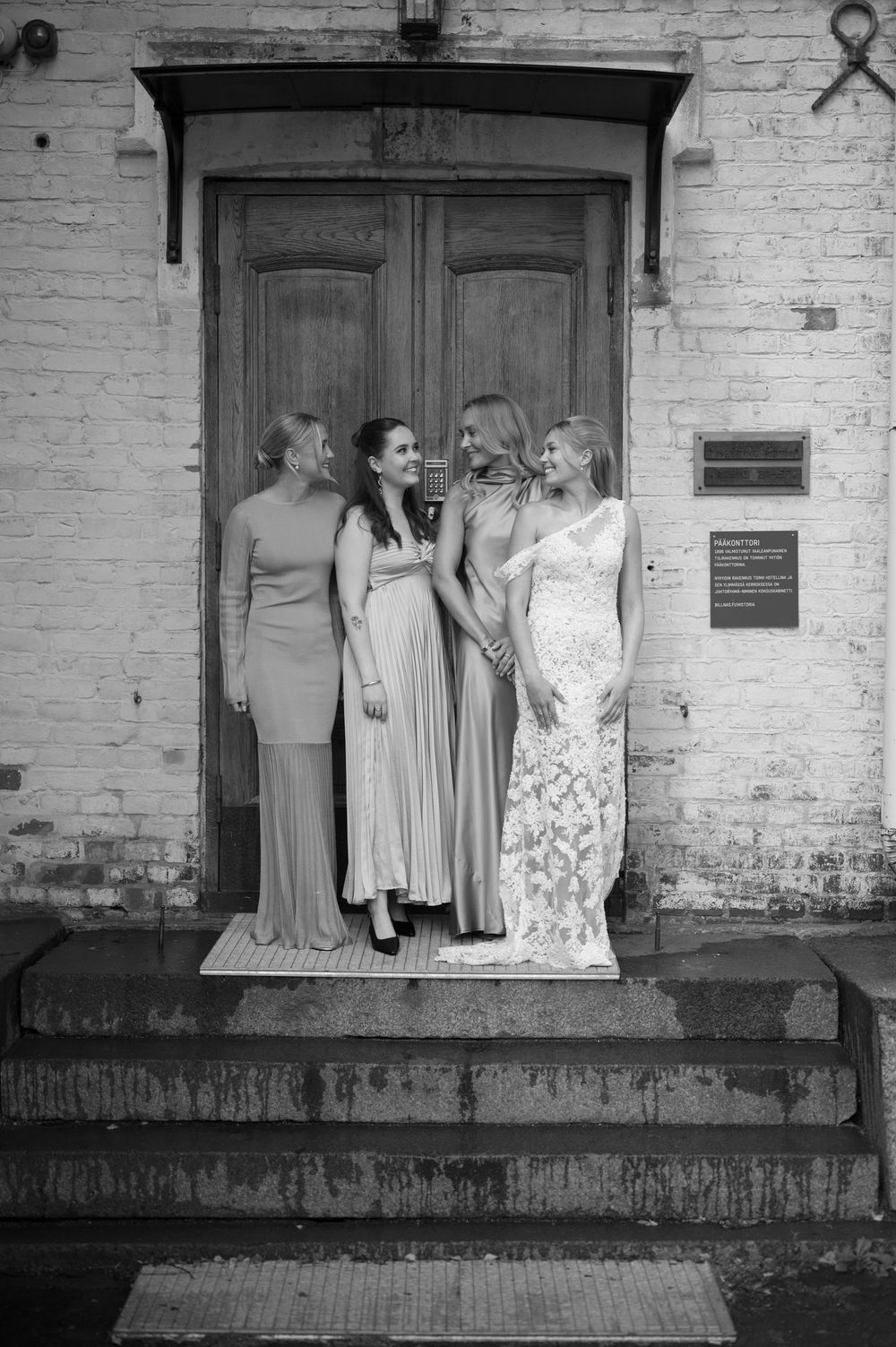 Wedding party poses informally on vintage building steps with exposed brick walls.