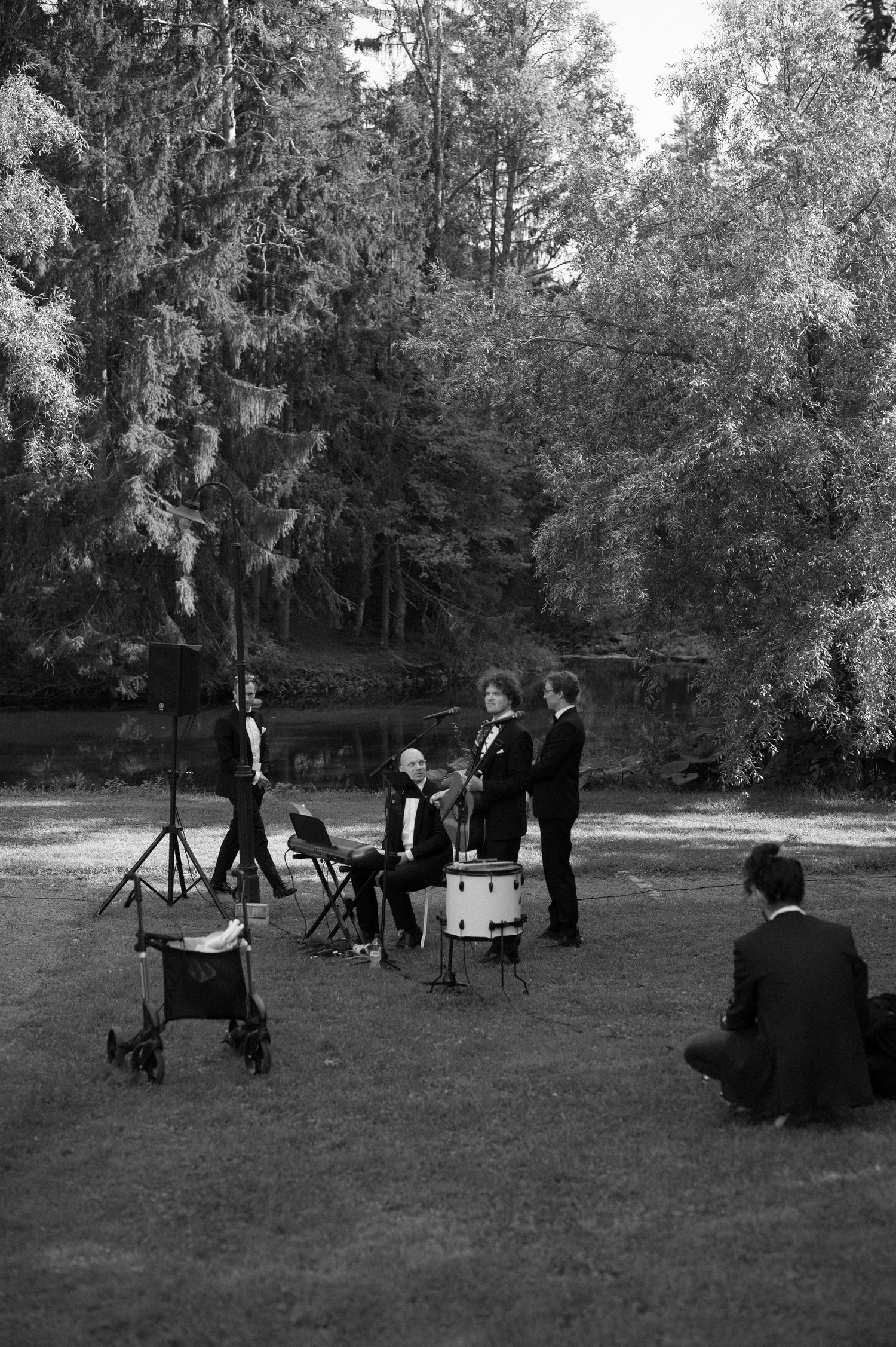 Wedding photographers capture candid moments during an outdoor ceremony in a wooded setting.