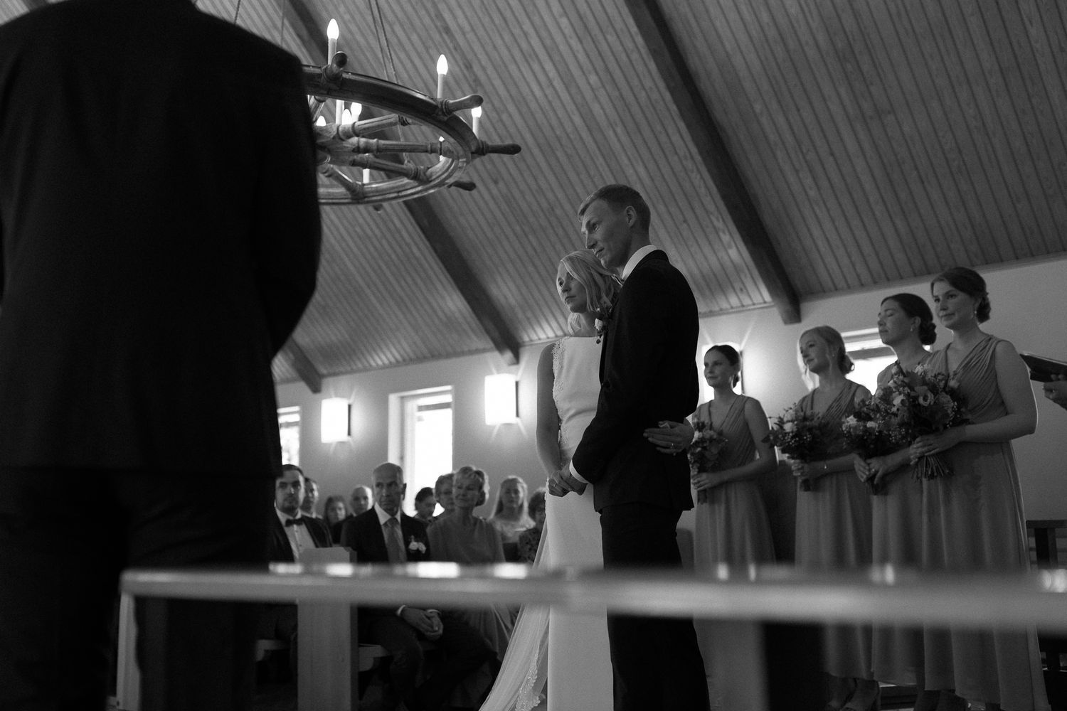 Artistic black and white shot of a wedding ceremony in a chapel with dramatic lighting.
