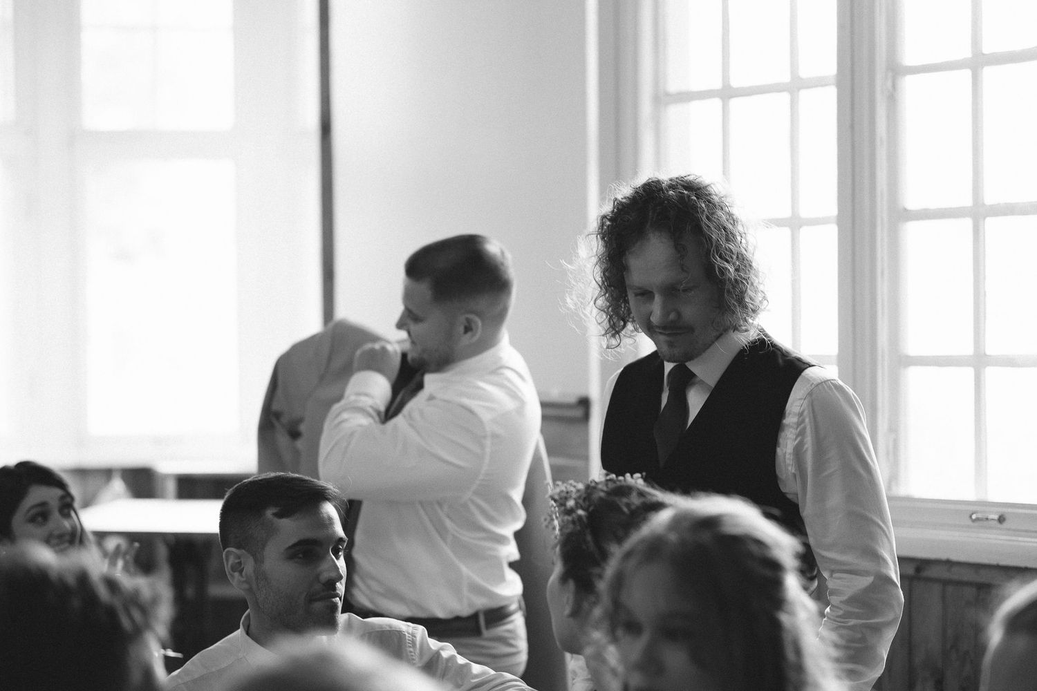 Bright sunlit reception venue with guests gathered at elegant dining tables.