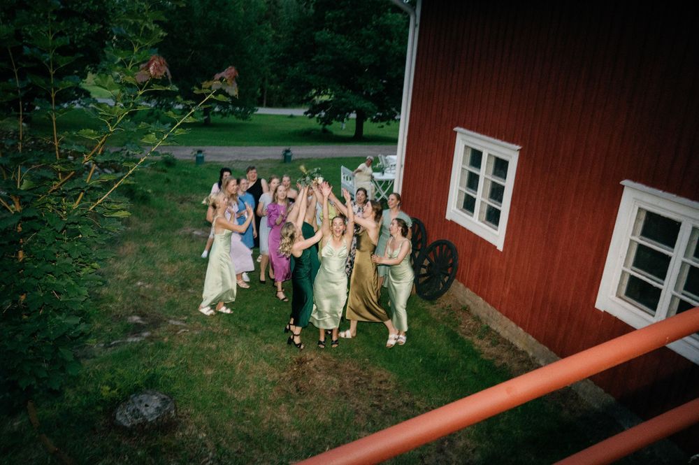Guests gather outside a red barn building during a wedding celebration.