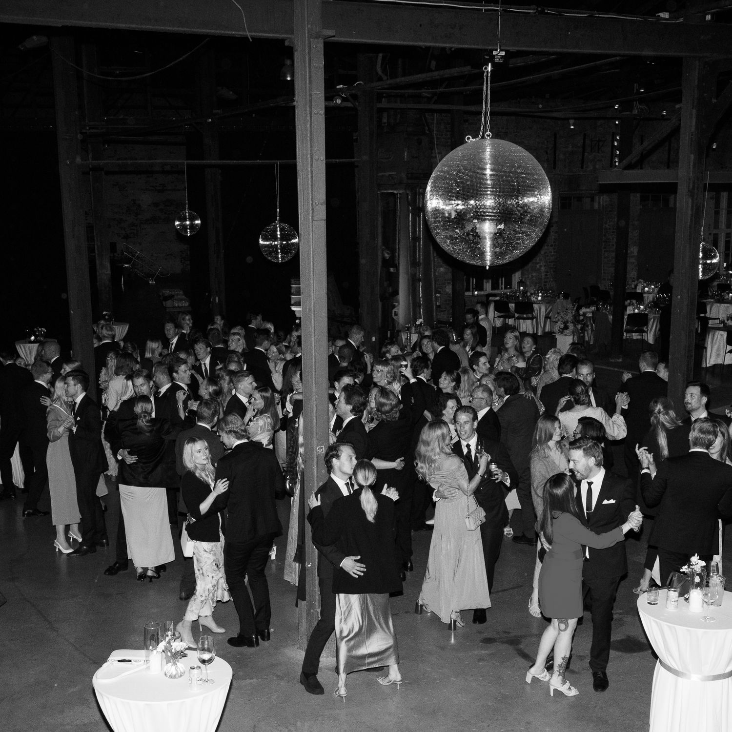 Large wedding reception dance floor with guests dancing under disco ball lighting.