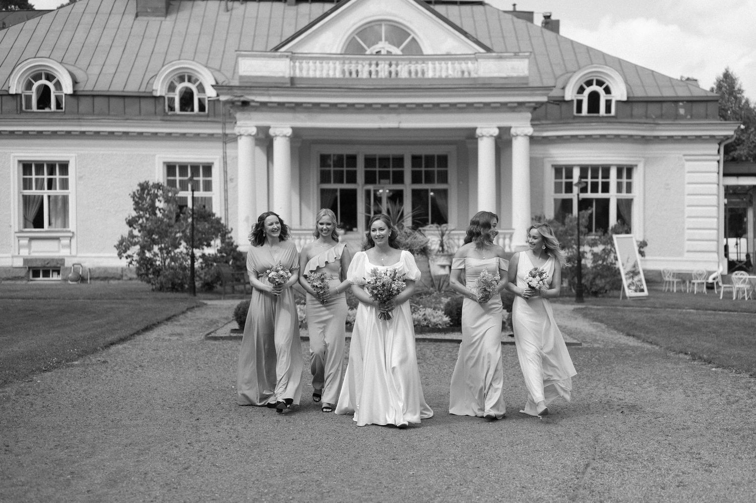 Black and white panoramic view of a historic estate building with wedding party on the grounds.