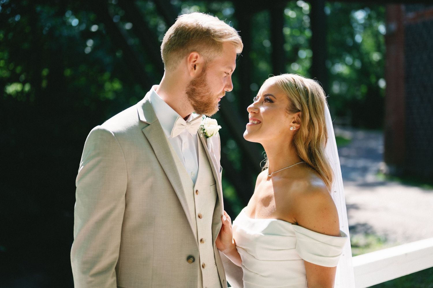 Romantic wedding couple shares joyful moments in a sunlit outdoor setting.