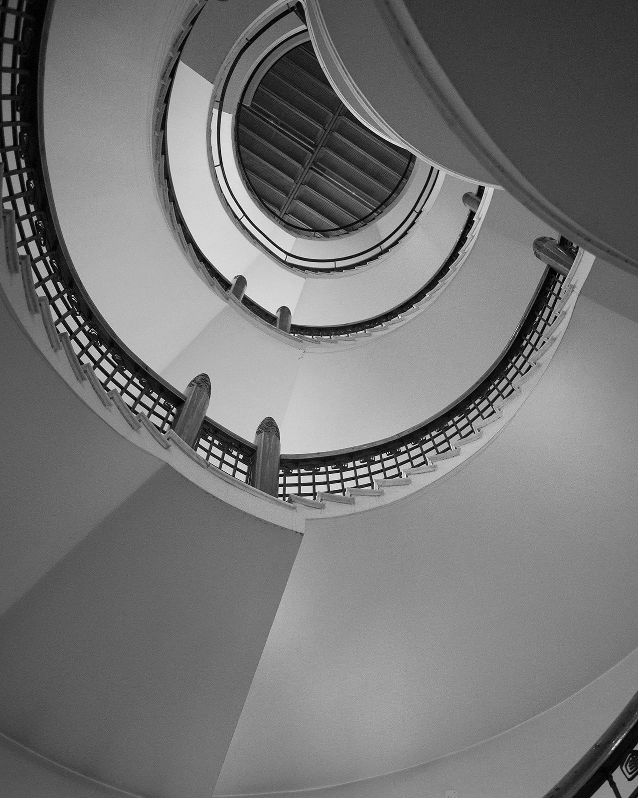 Dramatic spiral staircase photographed from below in black and white.