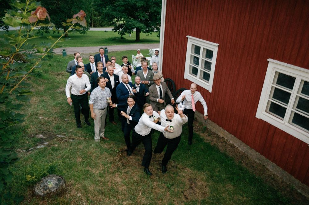 People celebrating at a rustic outdoor wedding near a red barn.