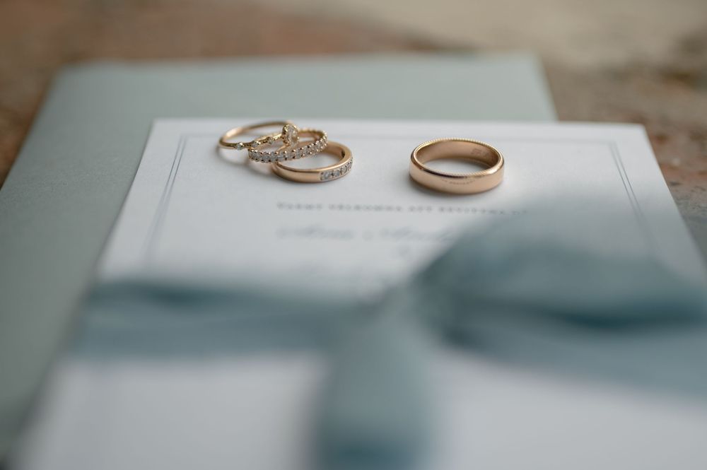 Wedding rings and elegant stationery arranged on light surface.