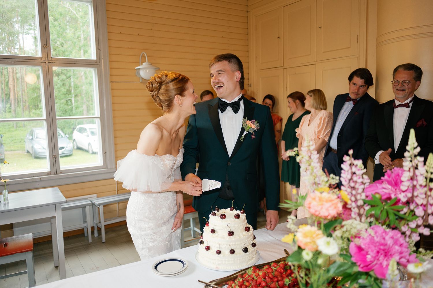 Elegant indoor wedding reception with pink floral arrangements and formal table settings.
