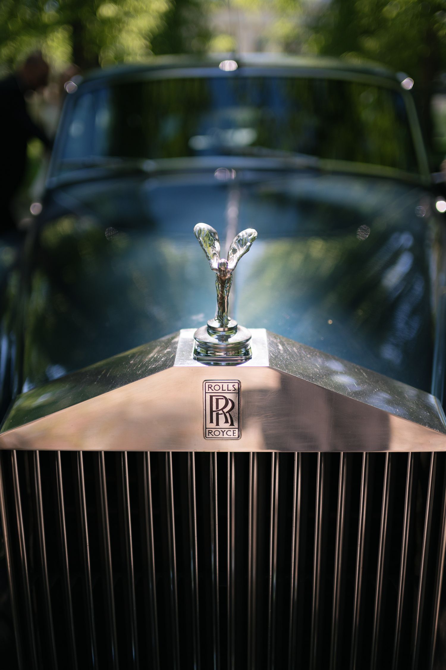 Close-up of a Rolls-Royce Spirit of Ecstasy hood ornament and grille badge on a vintage luxury car.