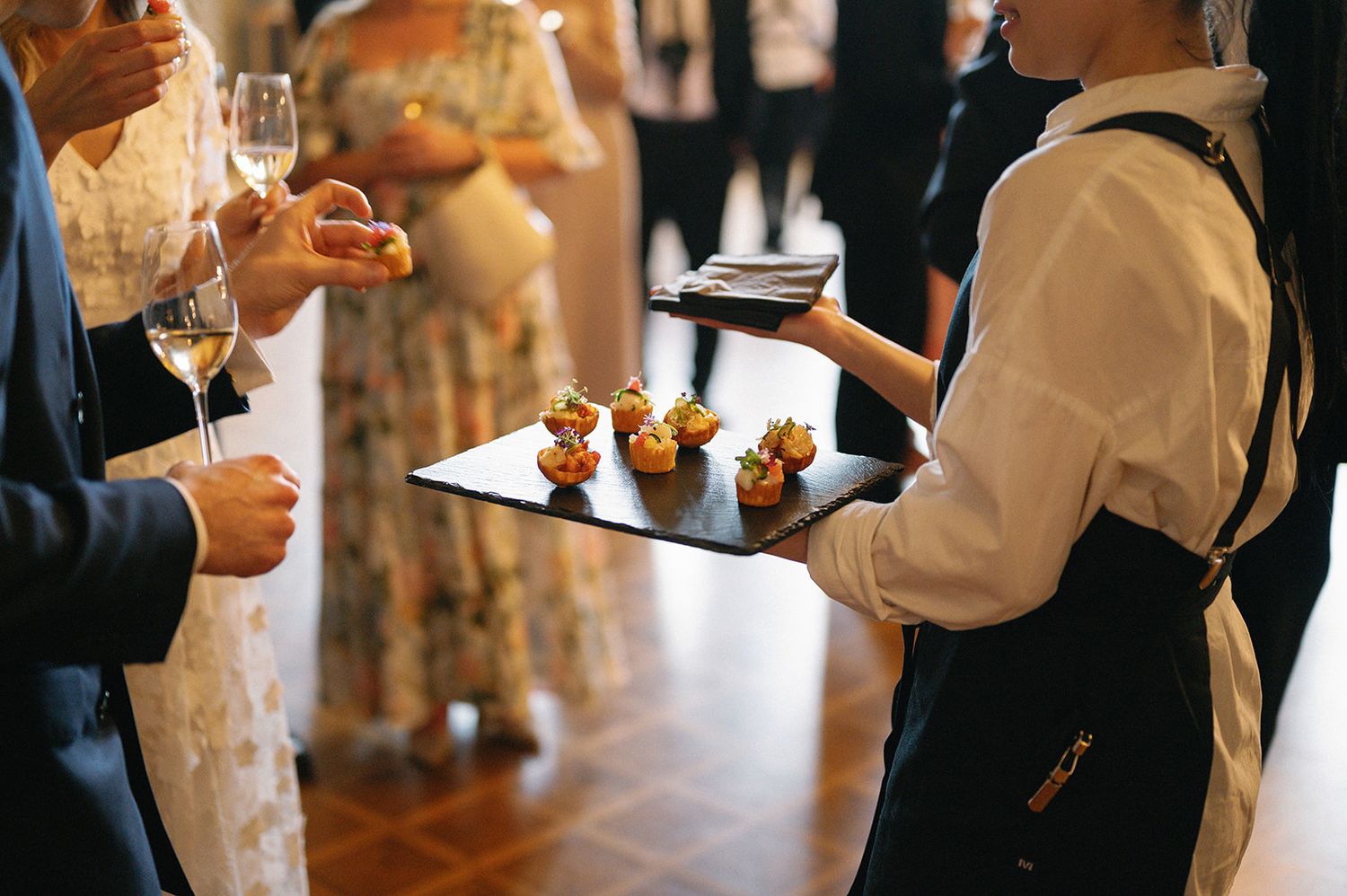 Wait staff in formal attire serving plates at an upscale dining event.