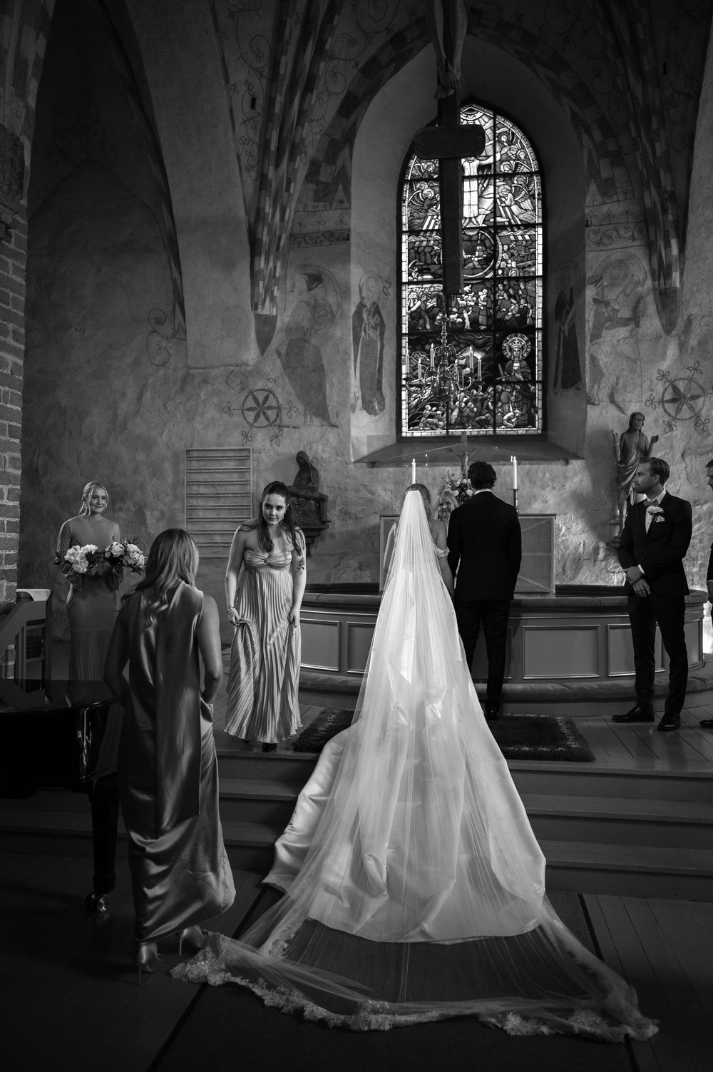 Black and white photo of a wedding ceremony in a historic church with dramatic lighting.