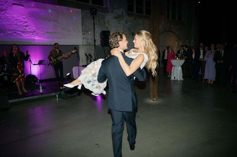 Dancers perform a dramatic spin move under purple lighting at a wedding reception.