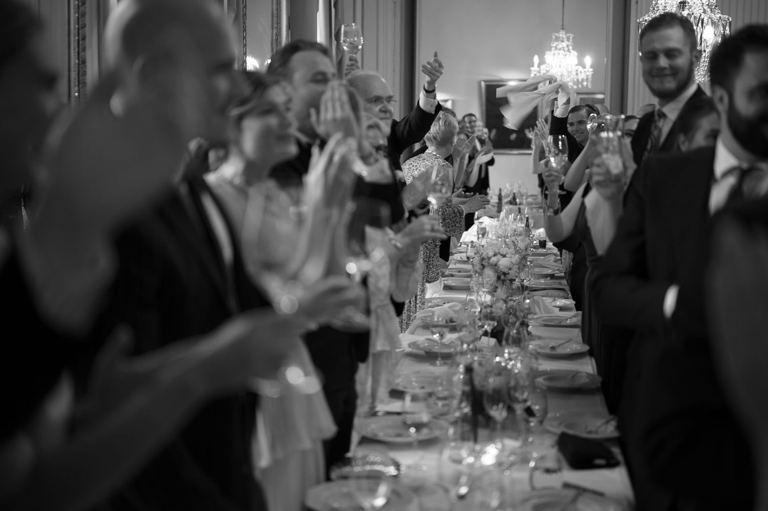 Wedding guests raise champagne glasses in celebration during an elegant reception dinner at a banquet hall.