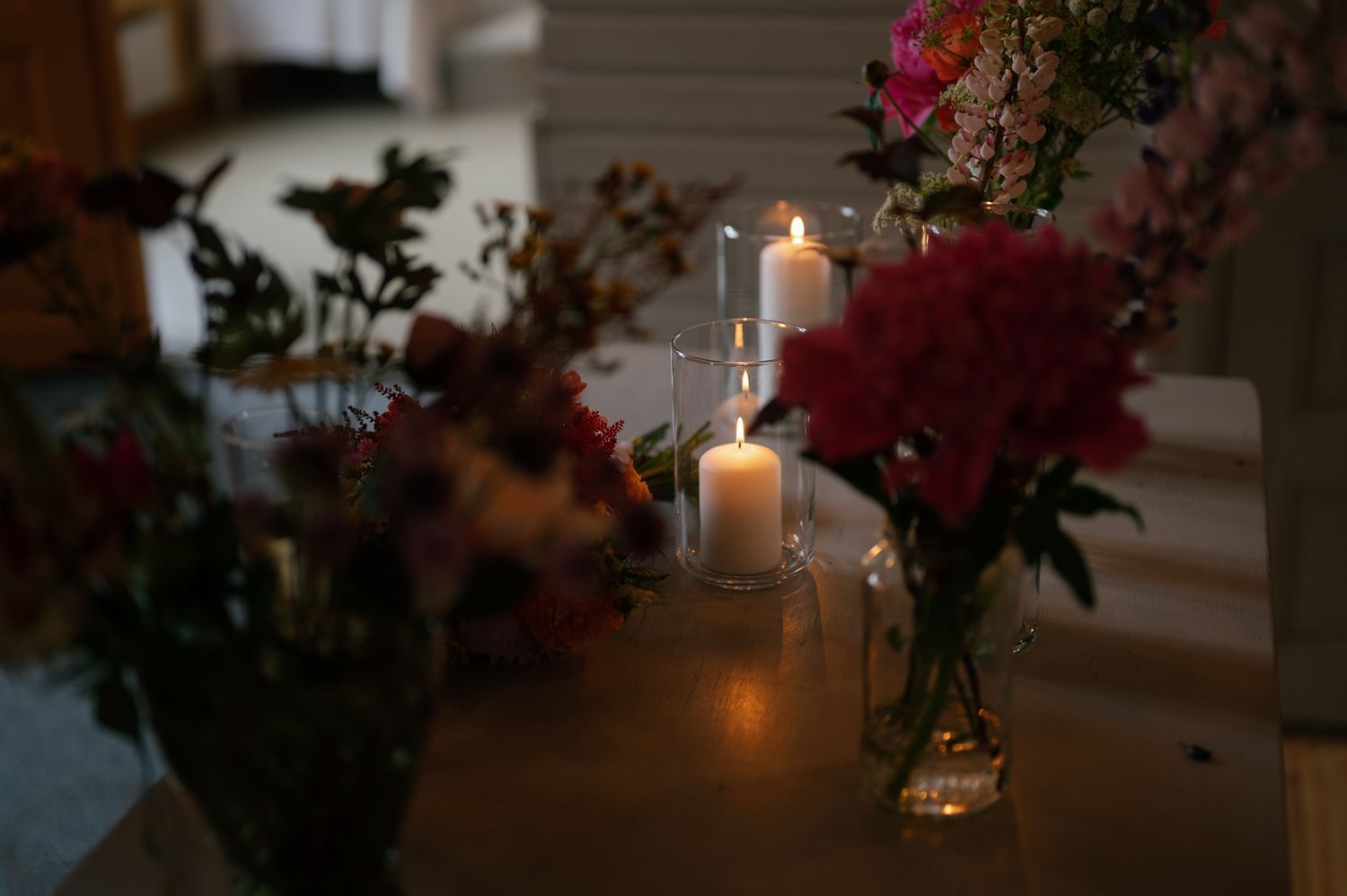 Romantic candlelit table setting with pink floral arrangements and glowing votives.