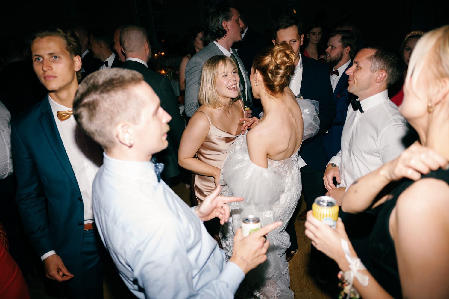 Wedding reception party with guests dancing under dark lighting.