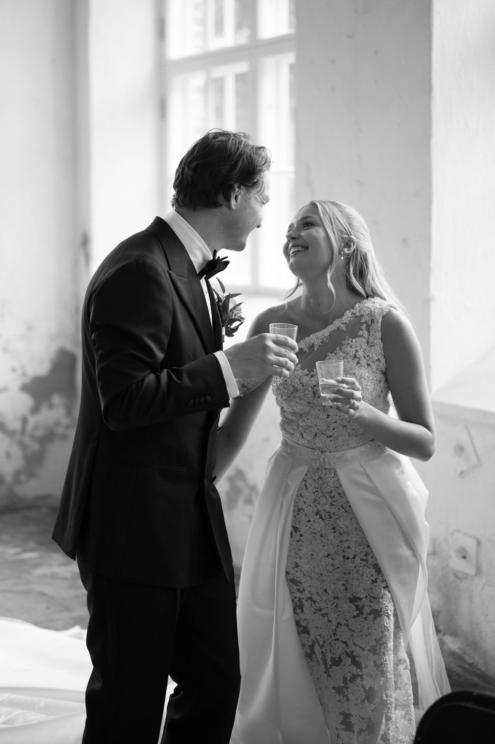 Intimate black and white moment between couple sharing drinks at wedding.