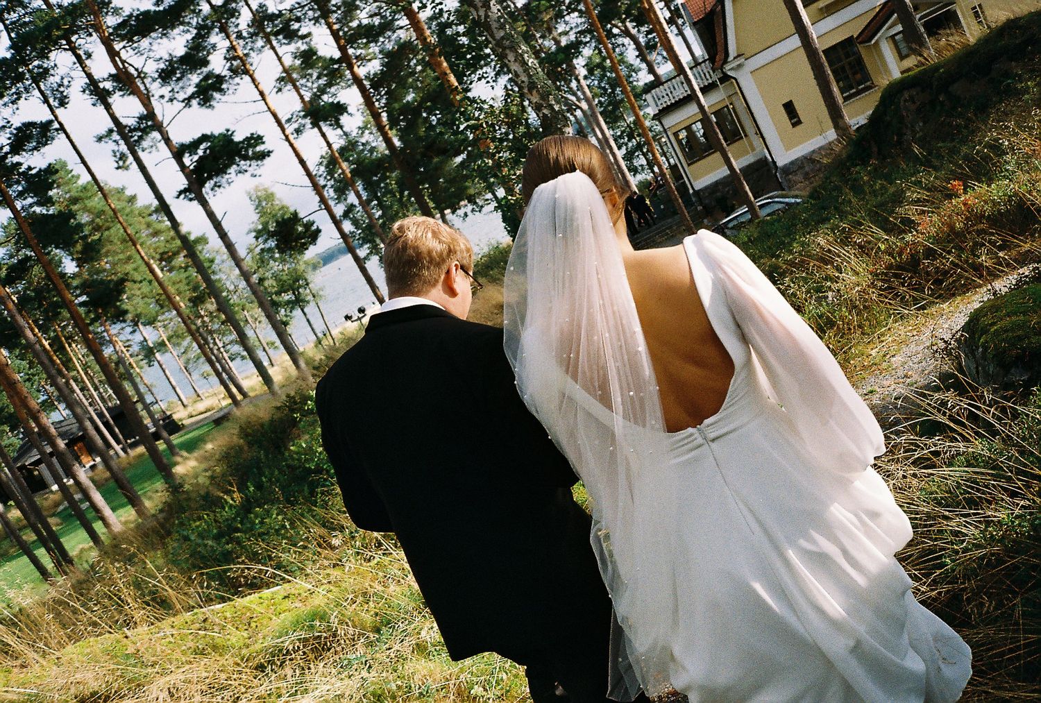 Wedding couple walking through wooded area in formal attire.