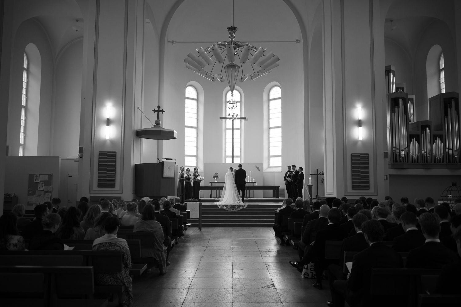 Interior view of a traditional white church sanctuary with stained glass windows and wooden pews during a service.