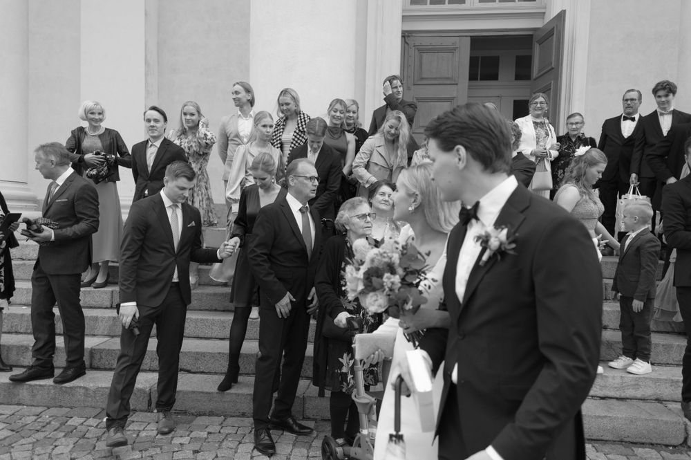 Wedding guests mingling outside a white classical building.