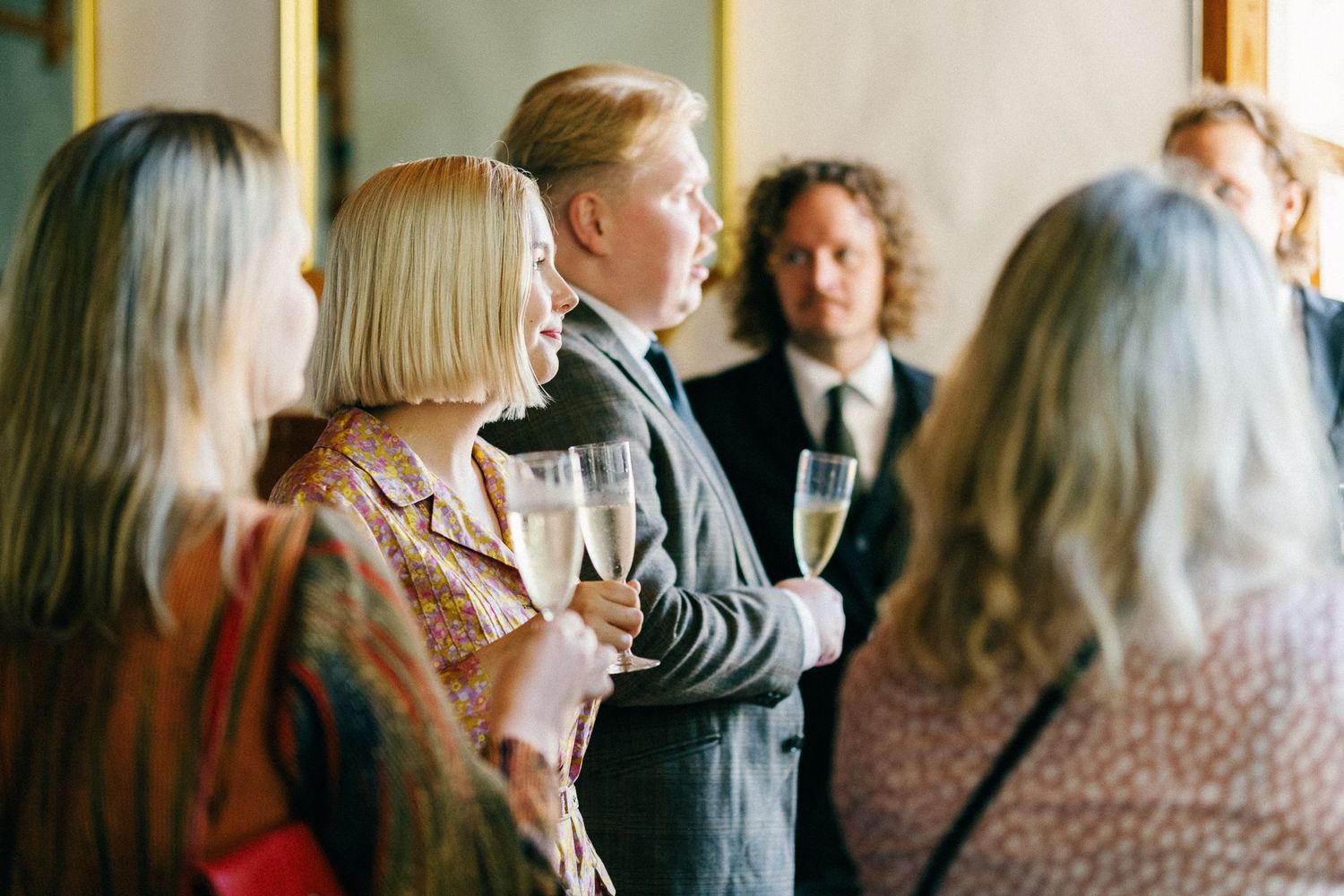 Wedding guests in casual attire mingle during an outdoor reception.