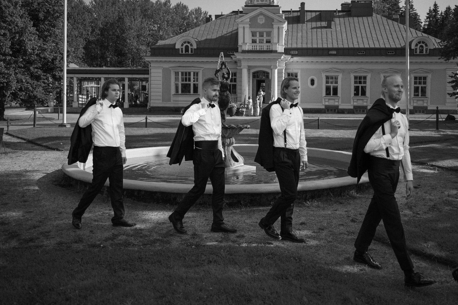 Wedding party walking along pathway outside historic yellow building.