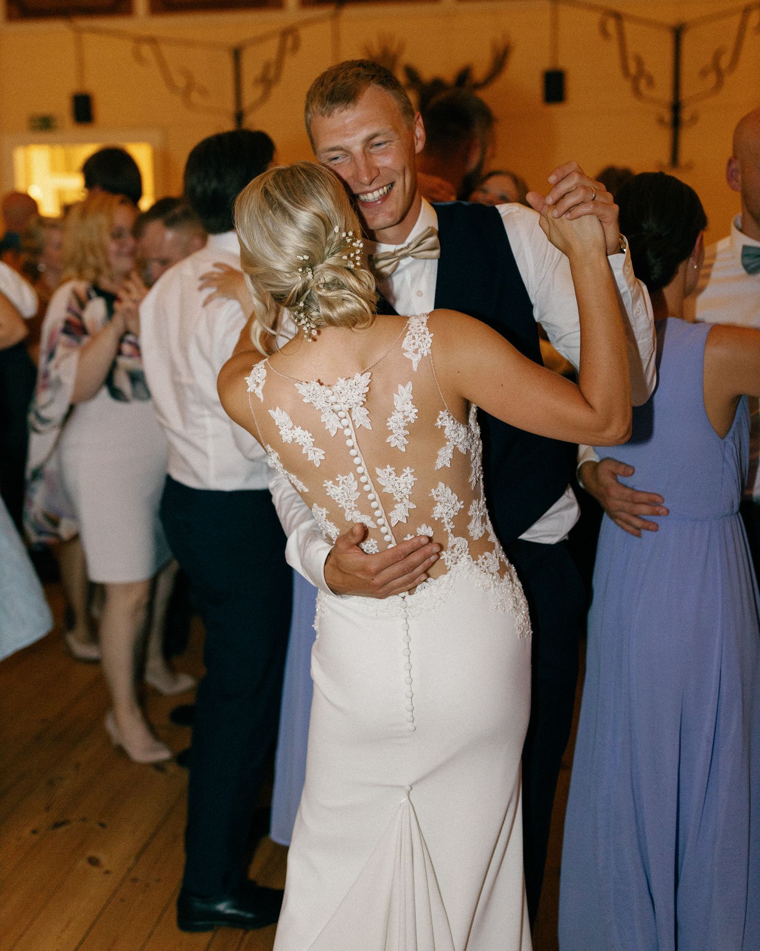 Wedding party members in blue dresses and formal attire dancing at the reception.