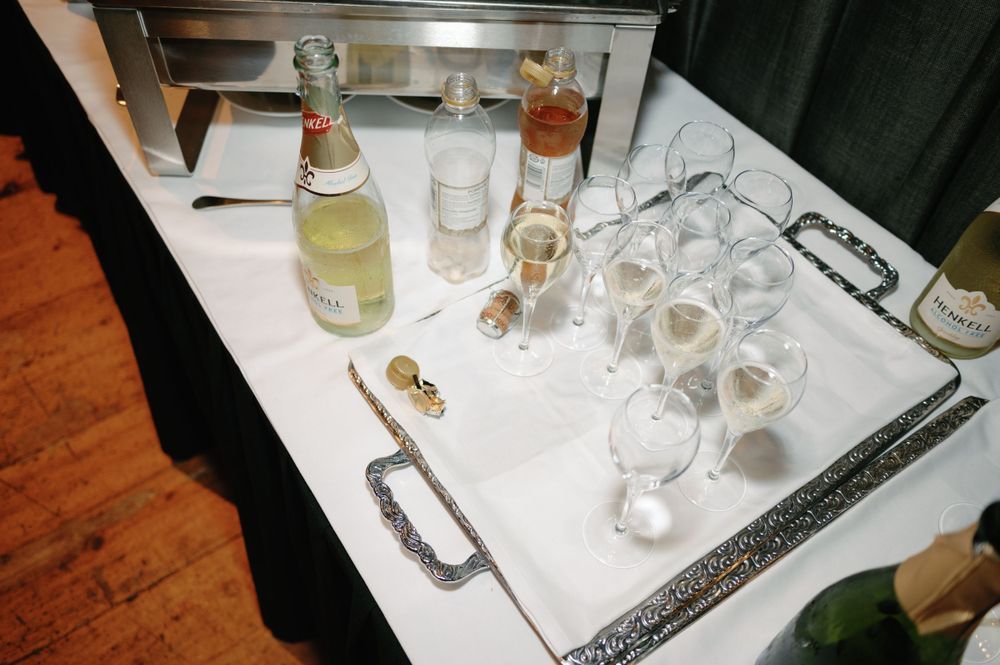 A bar setup with various glass bottles, cocktail glasses, and serving utensils on a white tablecloth.