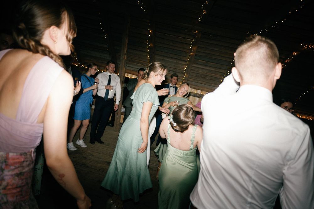 Crowded dance floor with party guests dancing under string lights.