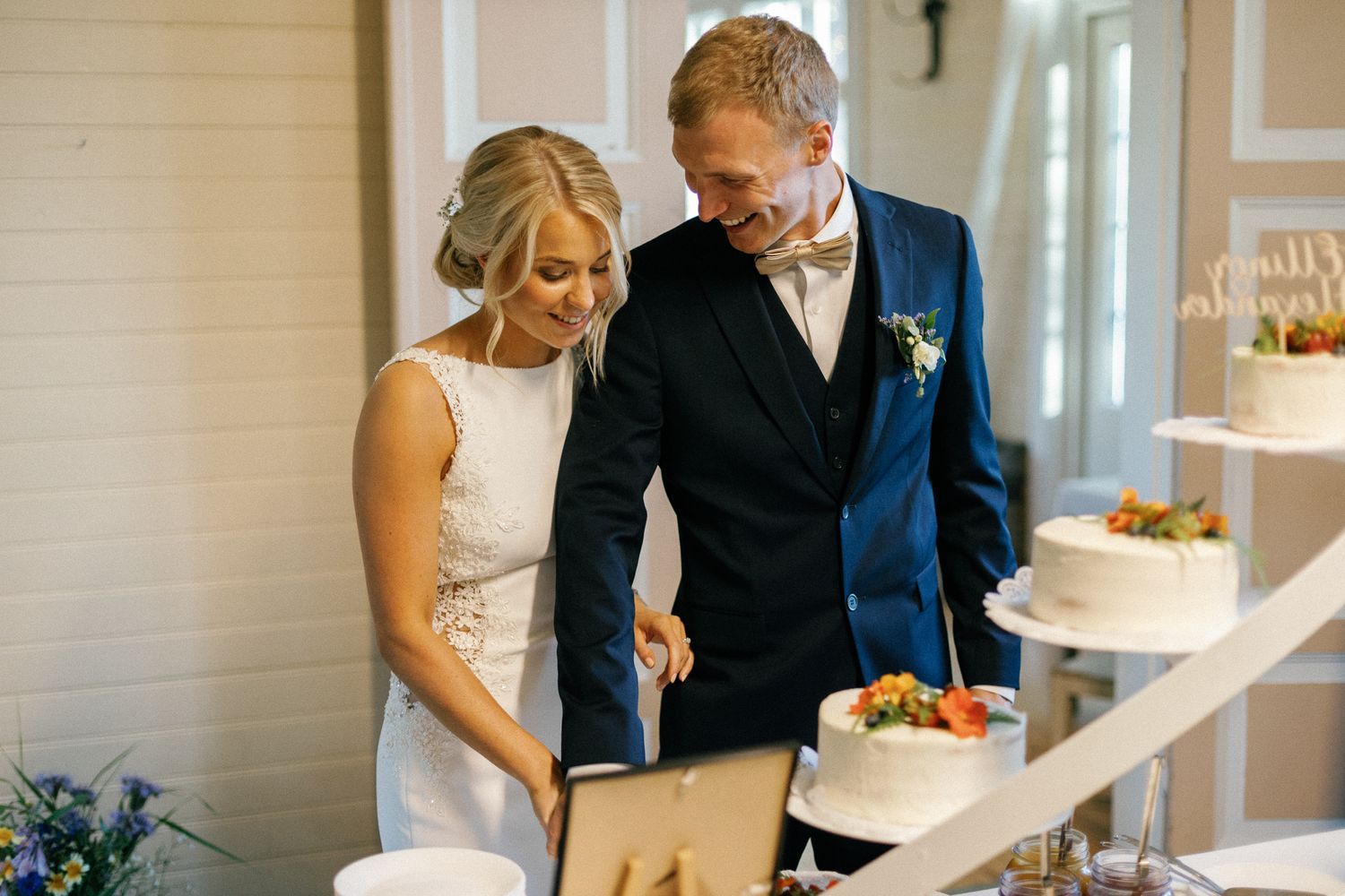 Elegant wedding reception setup with white linens and floral arrangements in an indoor venue.