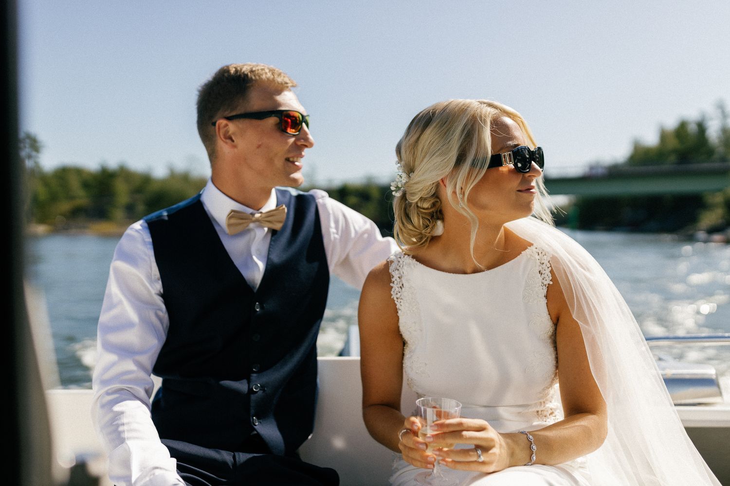 Stylishly dressed couple enjoying a boat ride on a sunny day.
