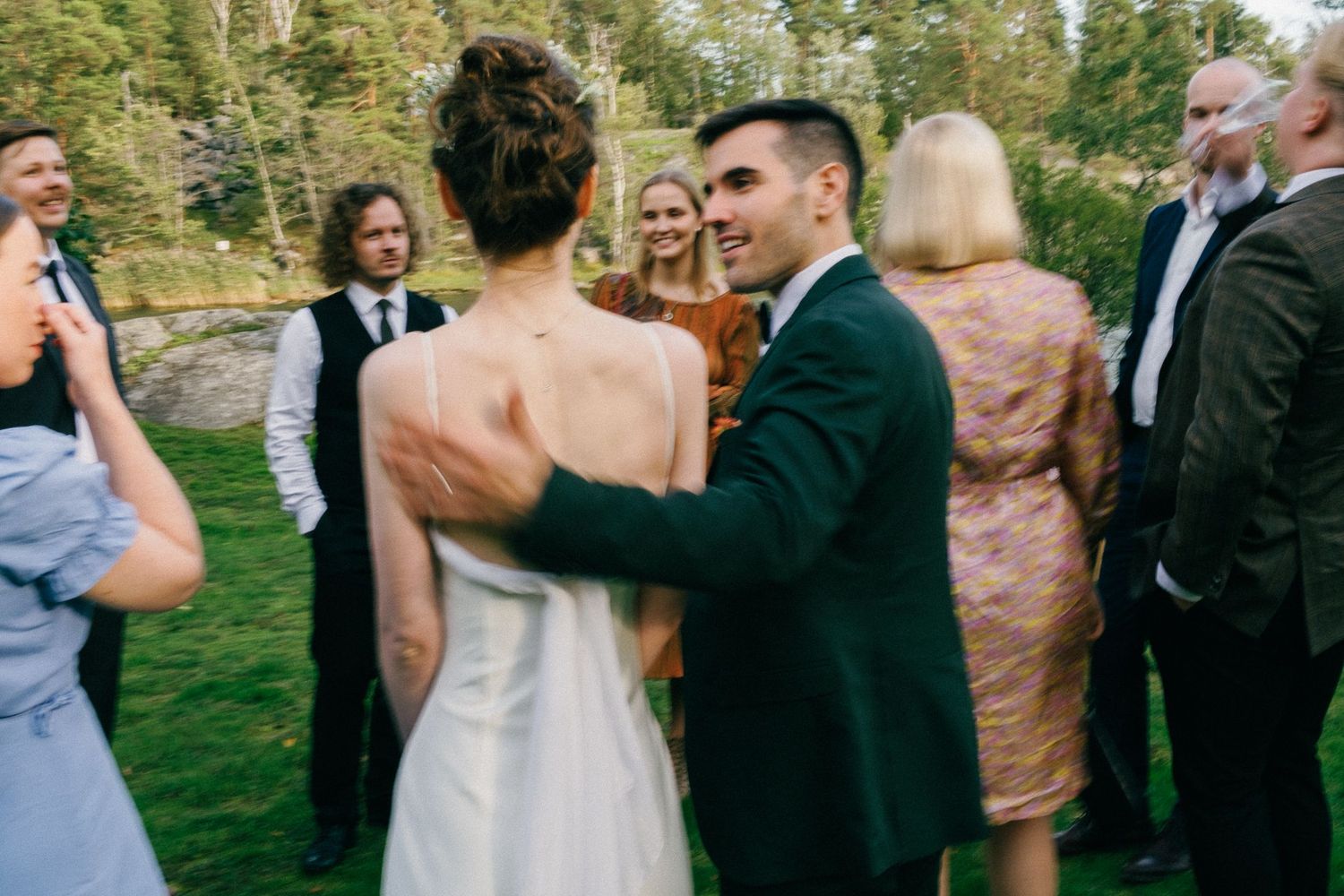 Wedding guests mingling outdoors on a grassy lawn during a sunny afternoon celebration.