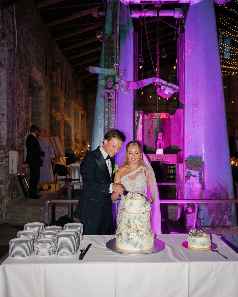 Wedding reception venue illuminated with purple uplighting and string lights creating a romantic atmosphere.