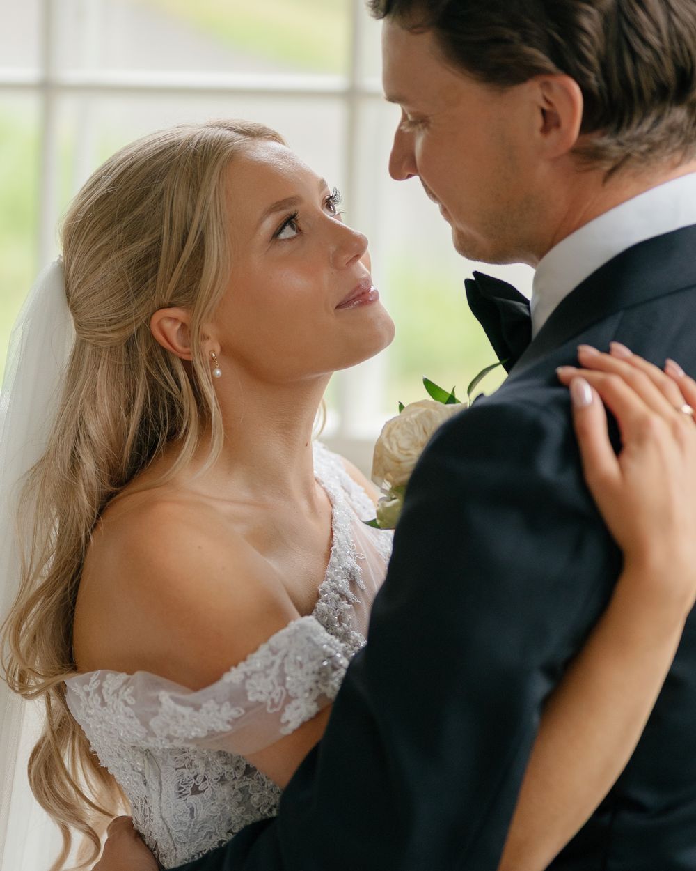 A close-up wedding portrait capturing an intimate moment between bride and groom in natural light.