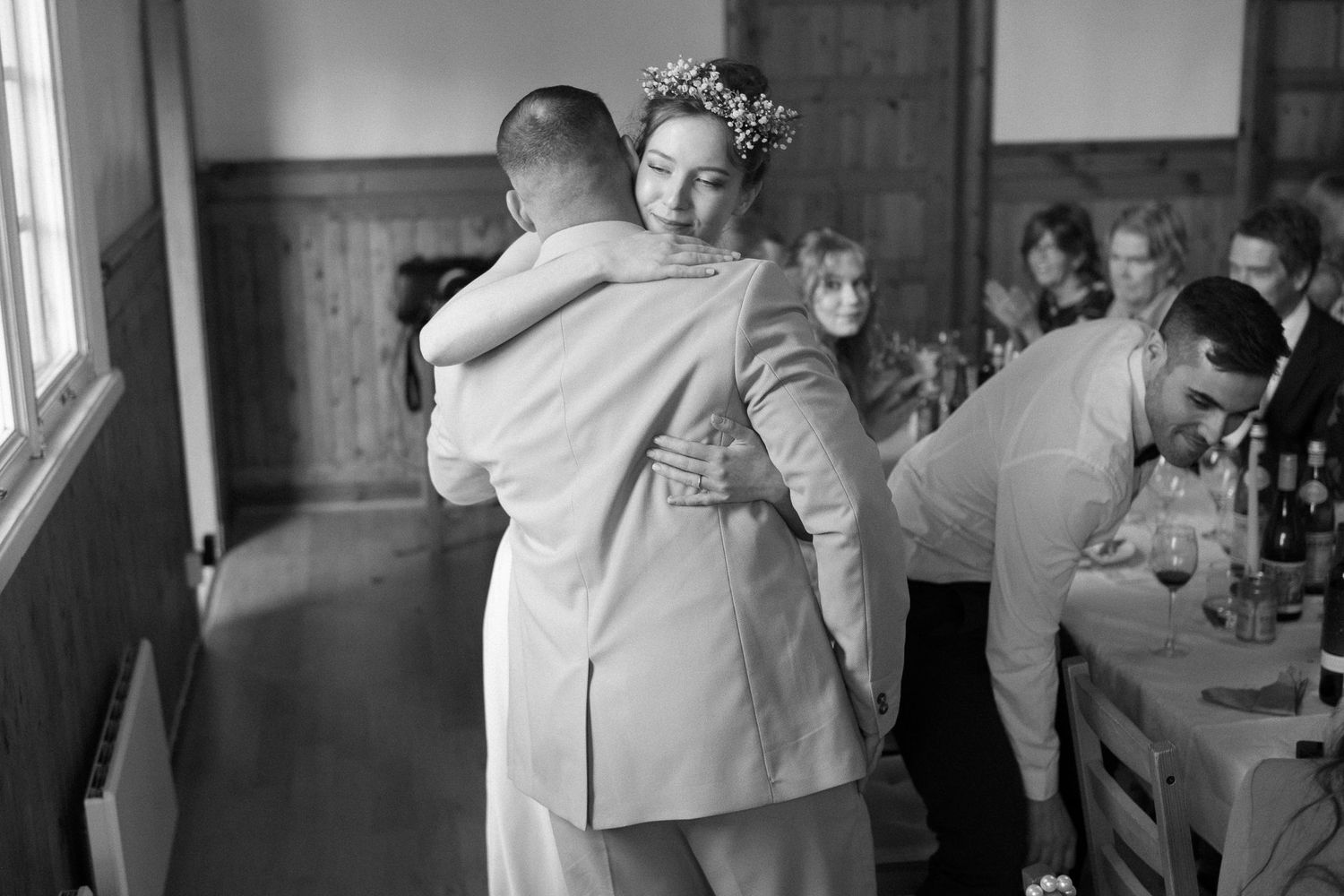 Emotional embraces shared during a wedding reception in a bright venue.