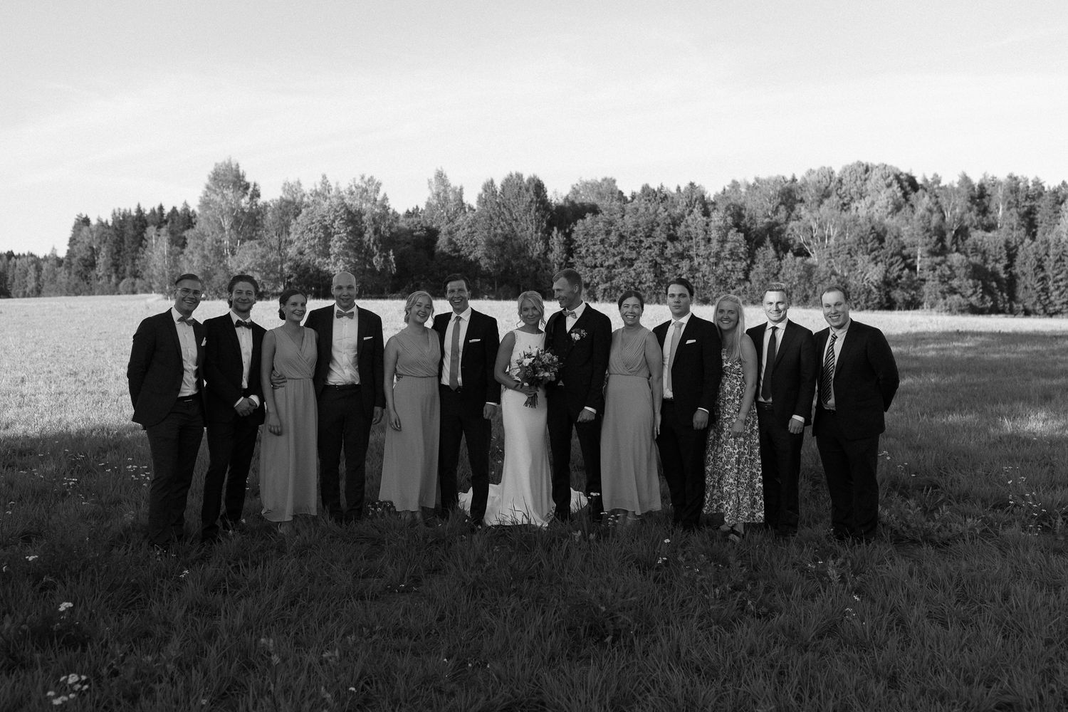 Wedding party silhouetted against horizon in black and white panoramic shot.