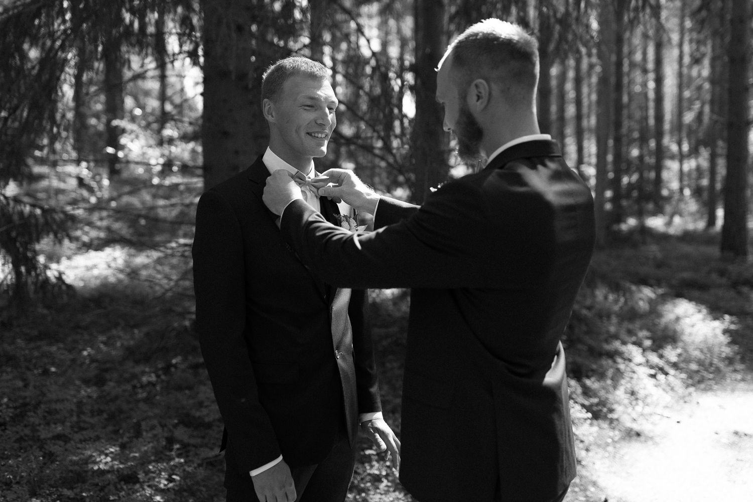 Two people share an intimate moment together on a sunlit forest path.
