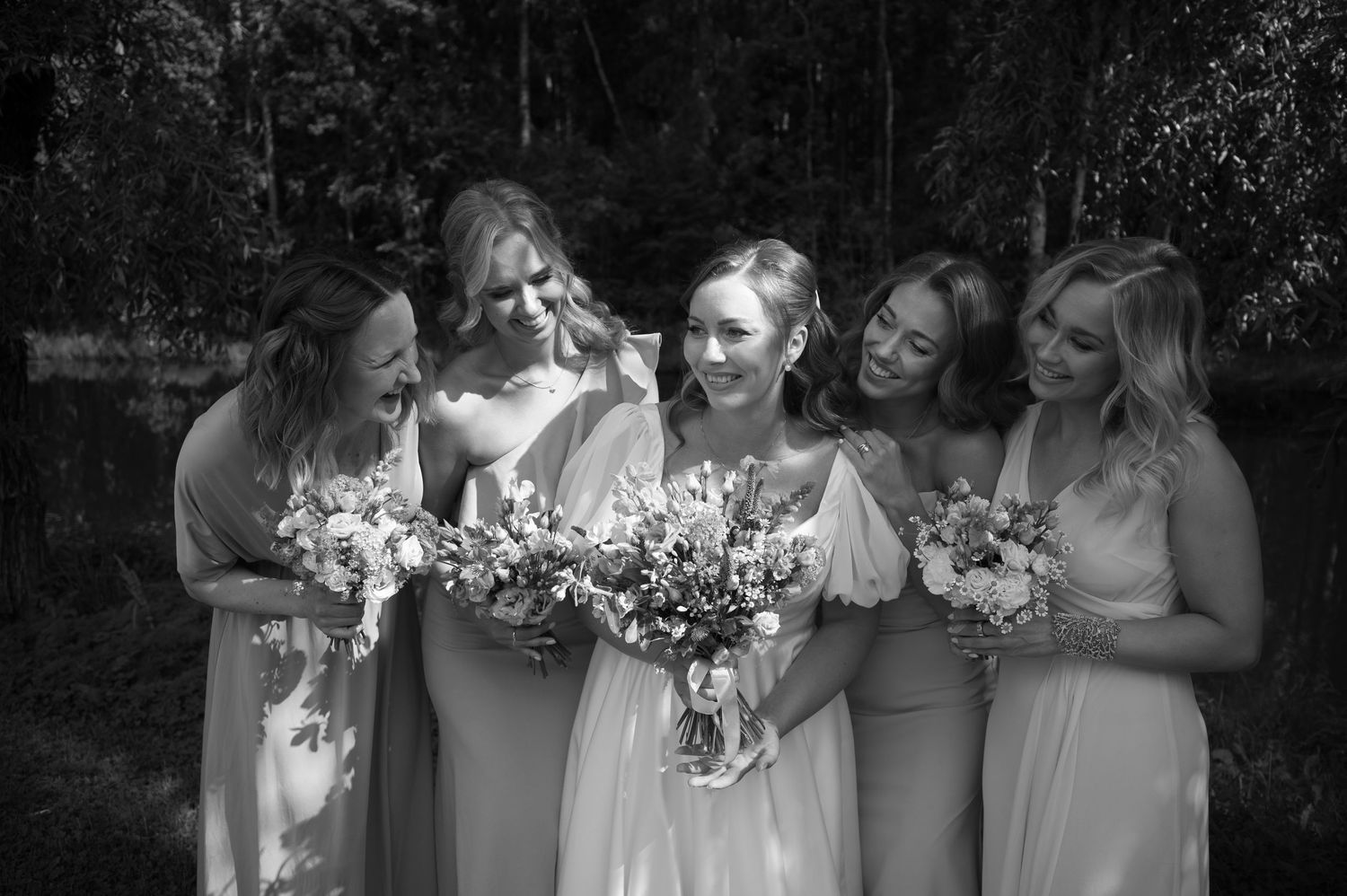 Wedding party holding bouquets in a candid black and white group photo.
