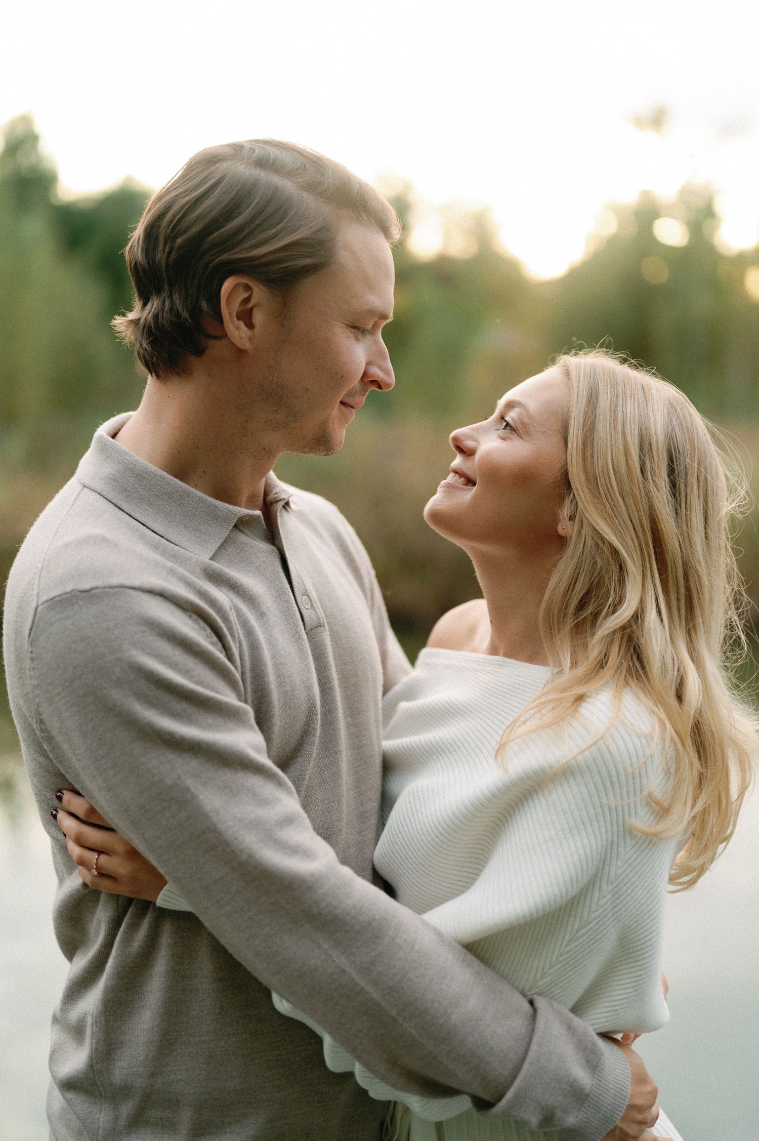 Romantic couple embracing and laughing together during a sunset photoshoot.
