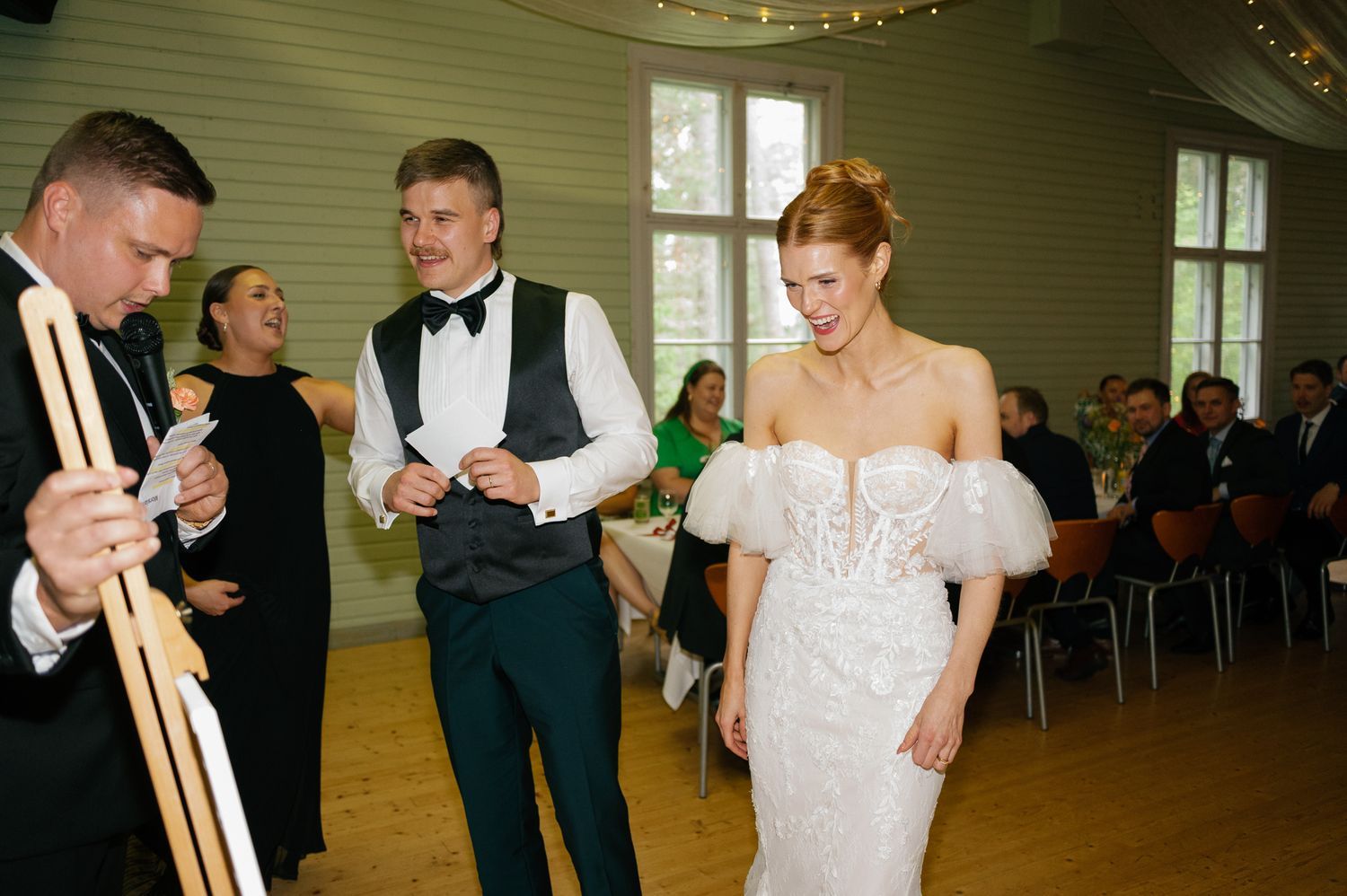 Elegant wedding reception with white draped ceiling and guests seated at decorated tables.