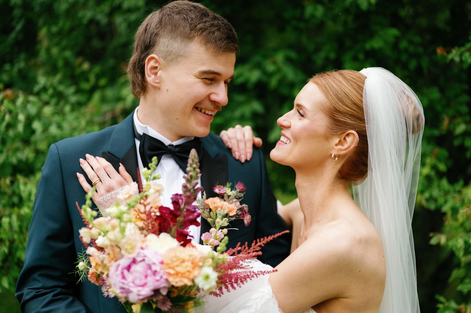 Wedding couple sharing romantic moment in garden with colorful summer flowers.