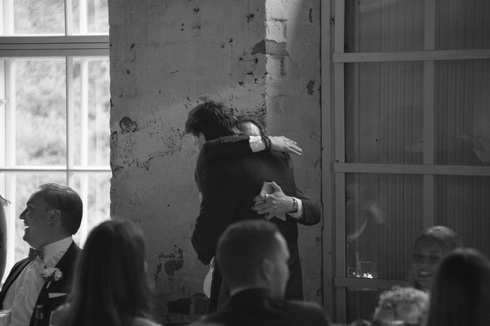 Black and white photo of an industrial-style venue with exposed brick walls and large windows.