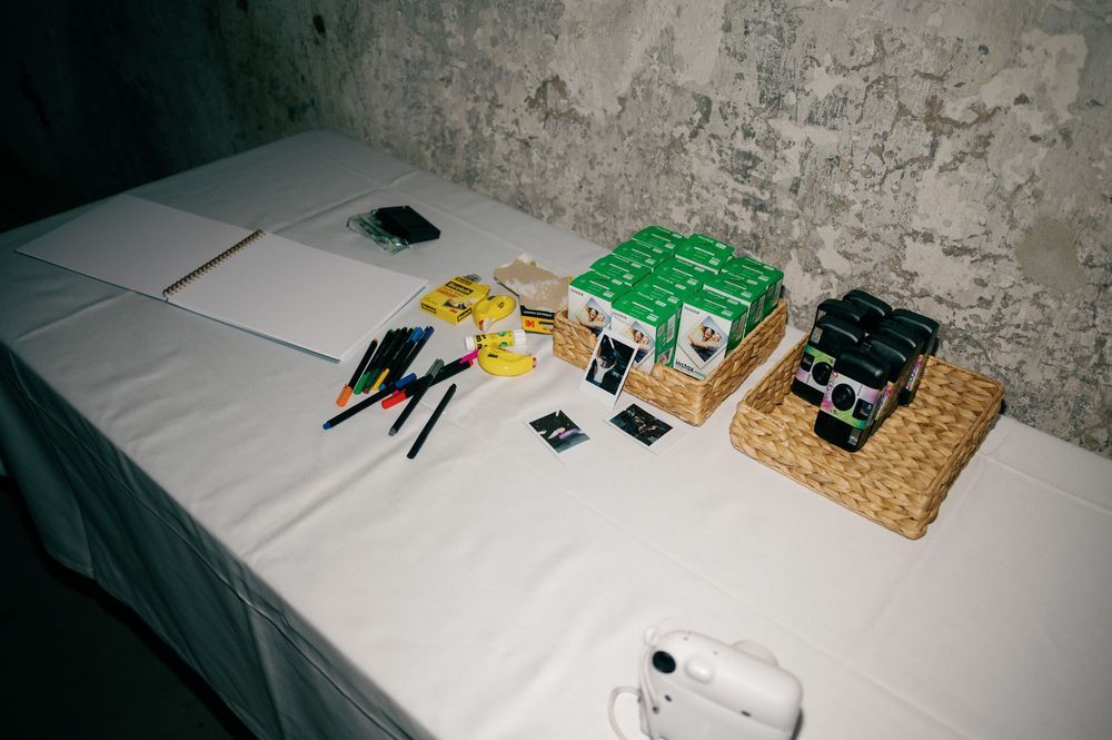 Wedding reception table with party favors and snacks laid out on white tablecloths.