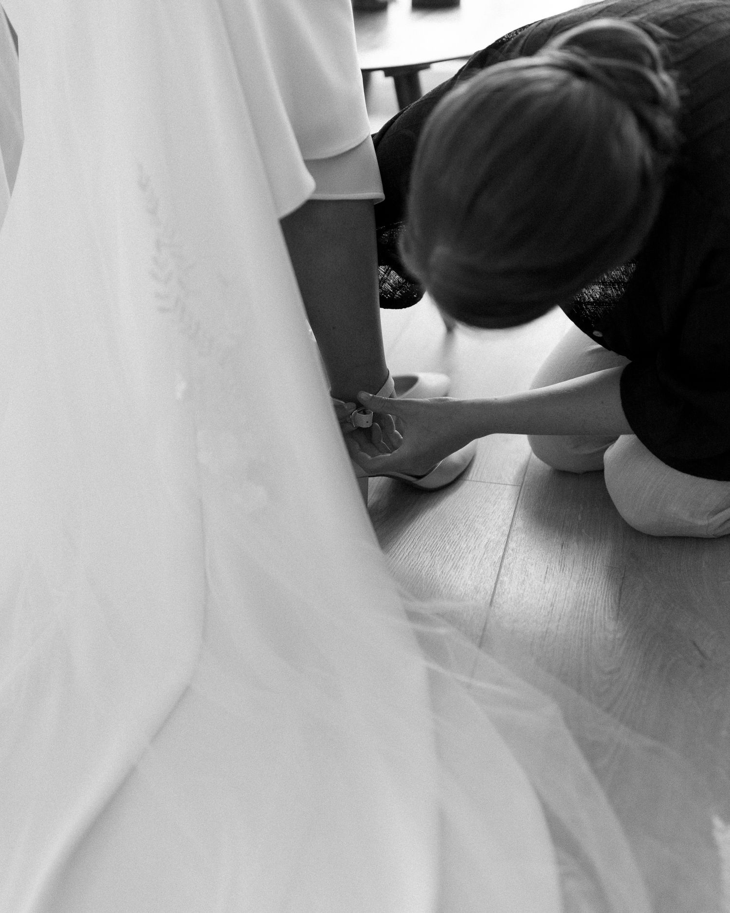 Close-up of flowing white wedding dress details in black and white.