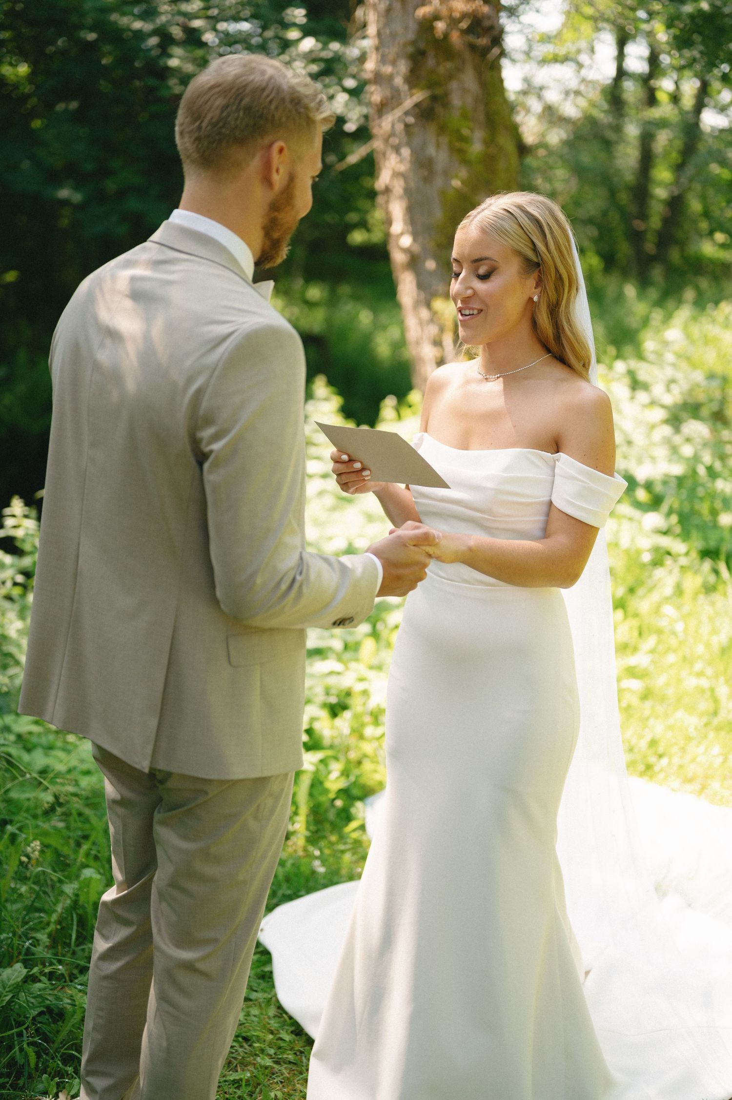 A couple shares intimate moments while exchanging letters during their outdoor wedding ceremony.