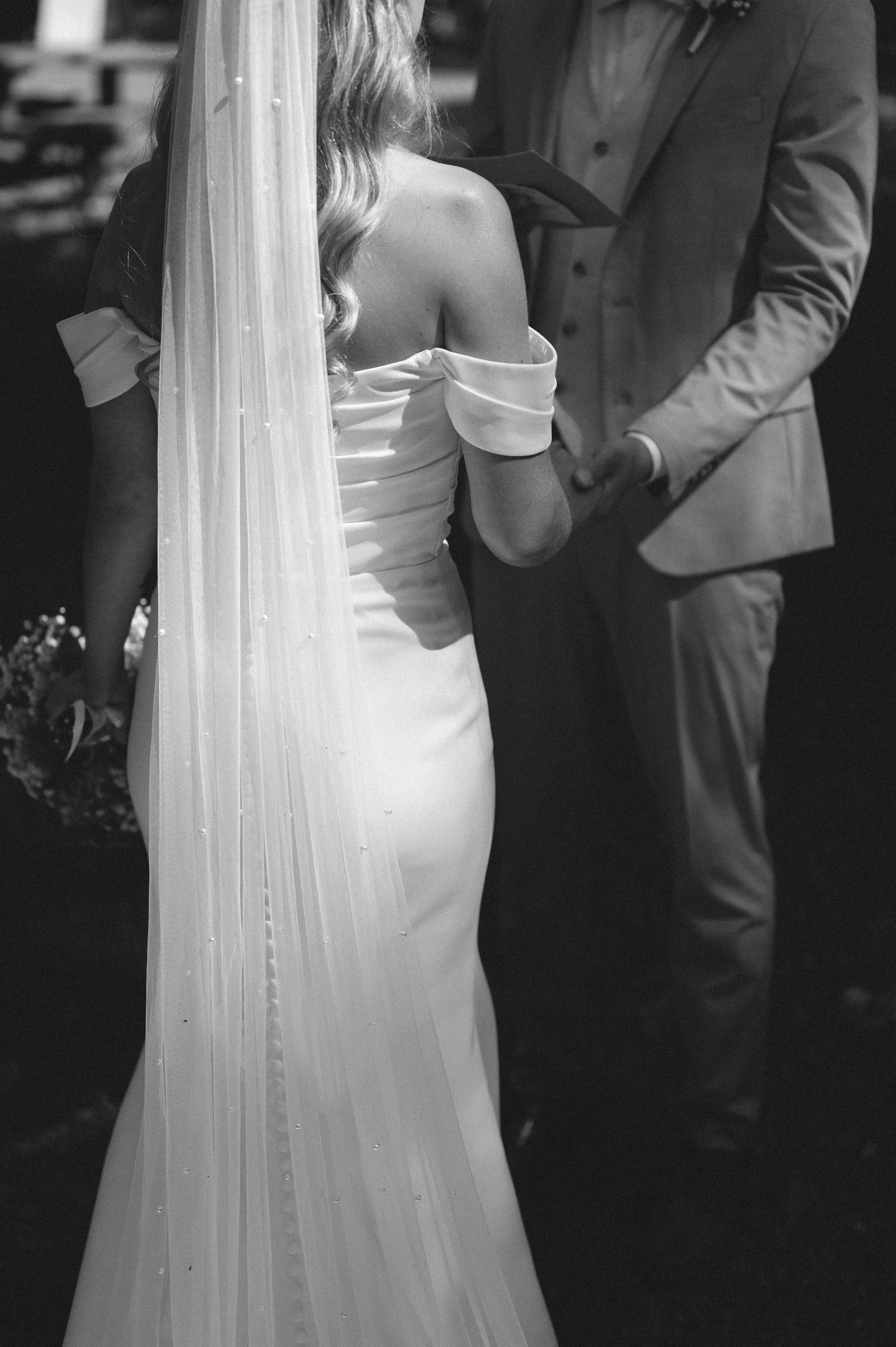 A couple in formal wedding attire stands close together during an intimate moment at their ceremony.
