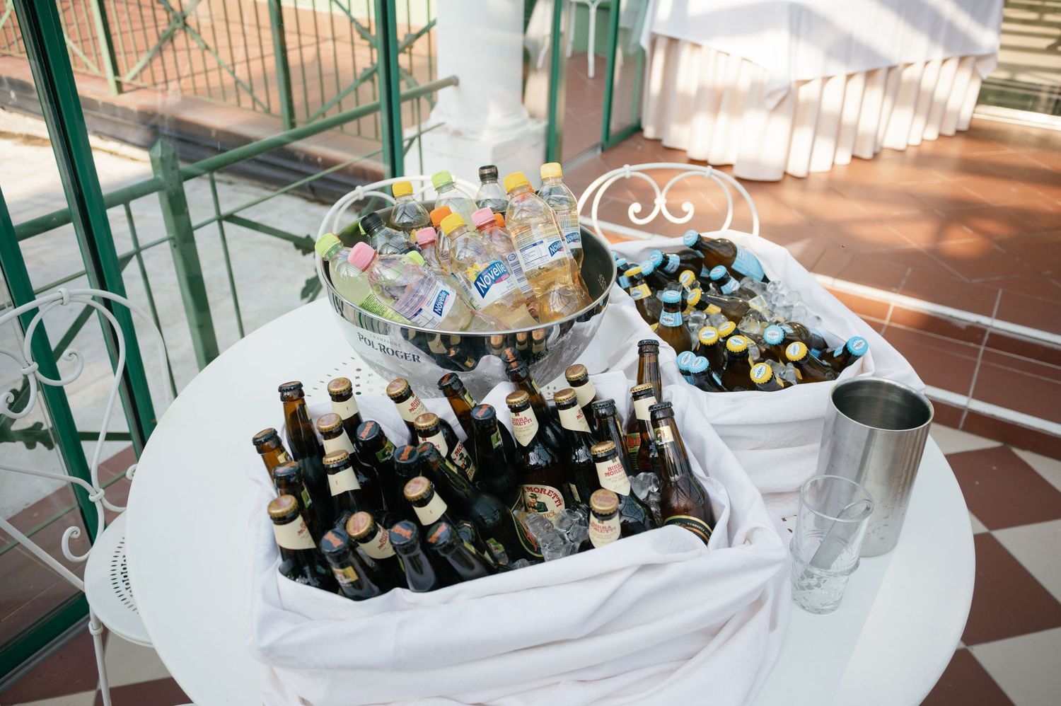 Champagne and beverages displayed on elegant white-clothed tables at outdoor reception.