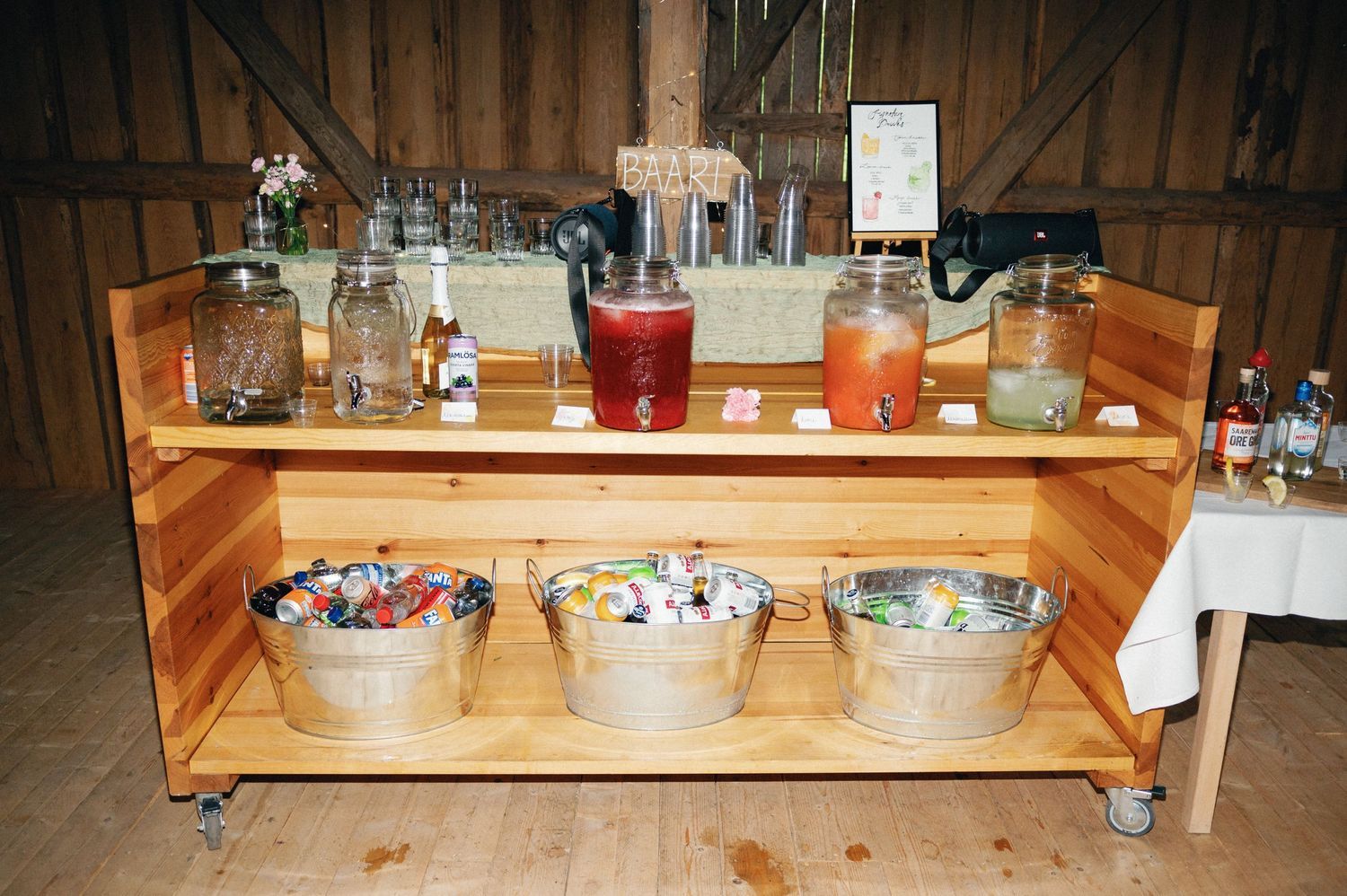 Row of vintage mason jars and glassware displayed on wooden shelving in a rustic barn venue.