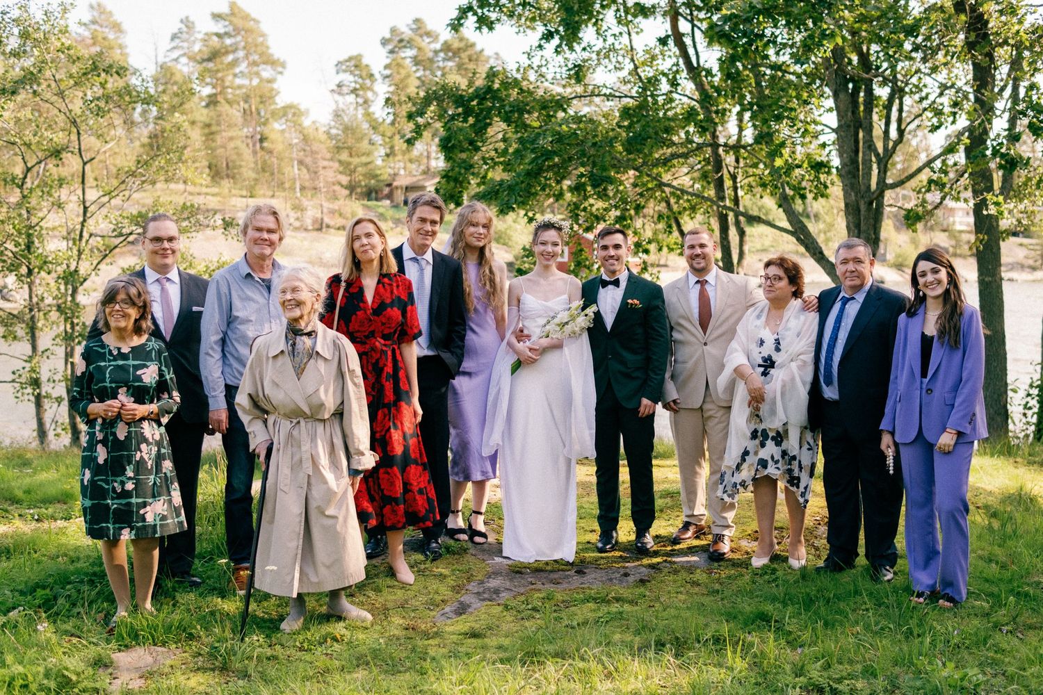 Large group photo of wedding guests standing together on a grassy lawn.