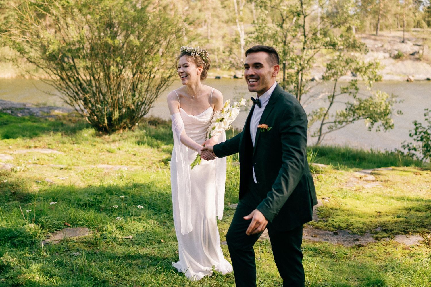 A couple shares a joyful moment together during their outdoor spring wedding by a river.